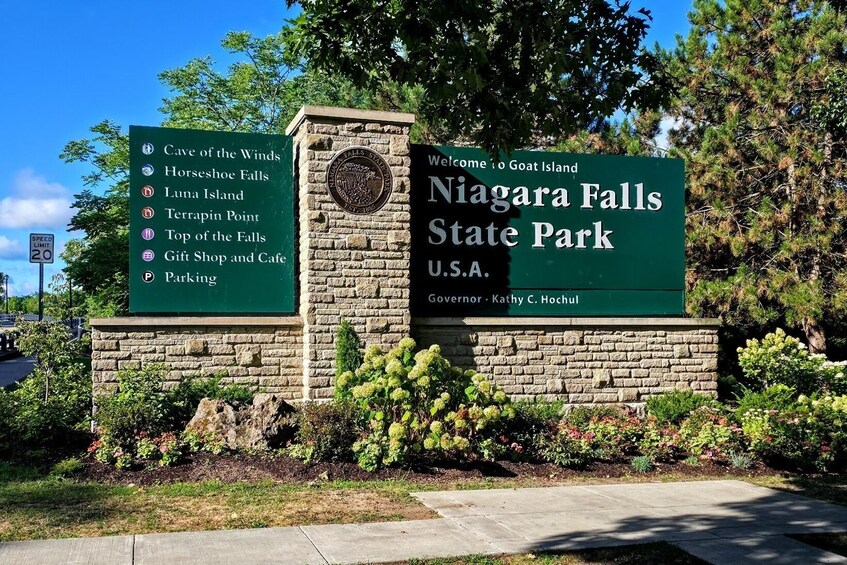 A sign for Niagara Falls State Park with a list of attractions and a welcome message. 1