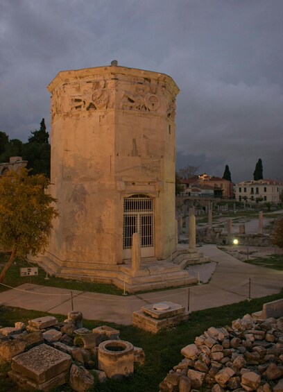 A historical stone tower with intricate carvings, surrounded by ruins and a pathway. 3