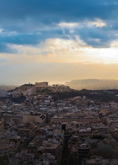 A cityscape with a prominent ancient citadel on a hill, surrounded by dense urban buildings. 5