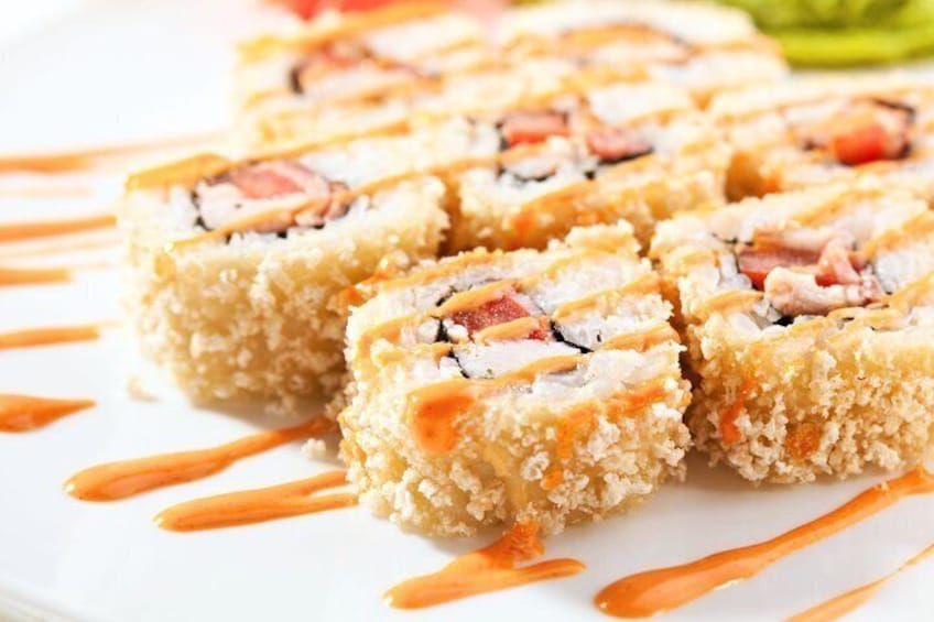 Sushi rolls with a crispy coating, drizzled with sauce, on a white plate. 5