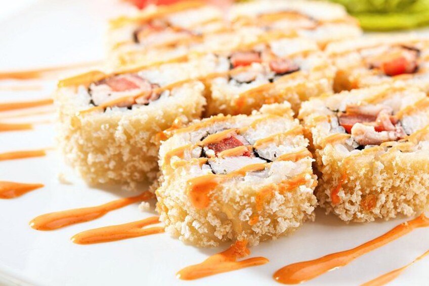 Sushi rolls with a crispy coating, drizzled with sauce, on a white plate. 3