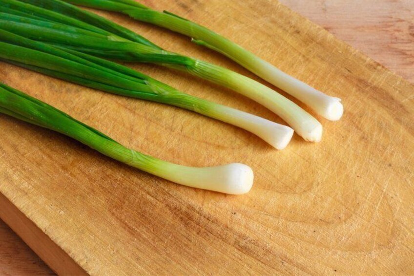 Green onions on a wooden cutting board. 4
