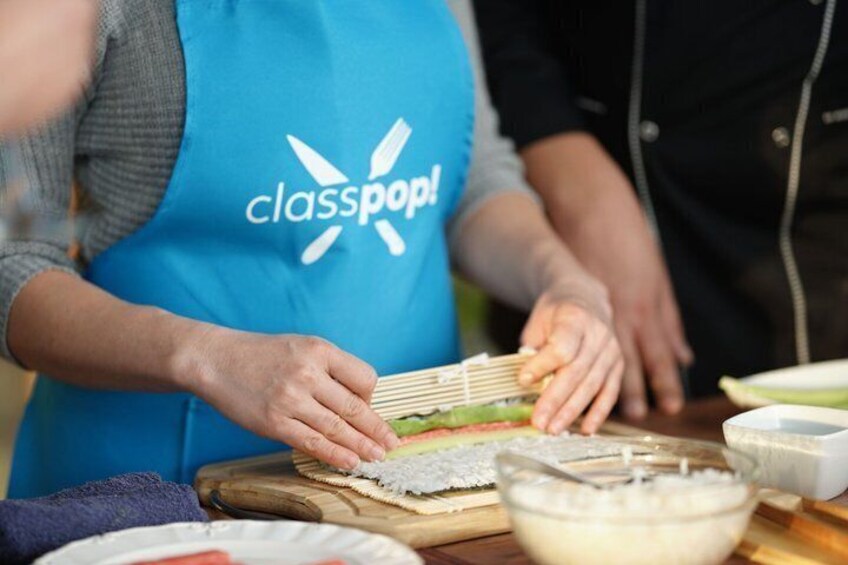 A person in a blue apron with 'classpop!' logo preparing food on a wooden board. 4