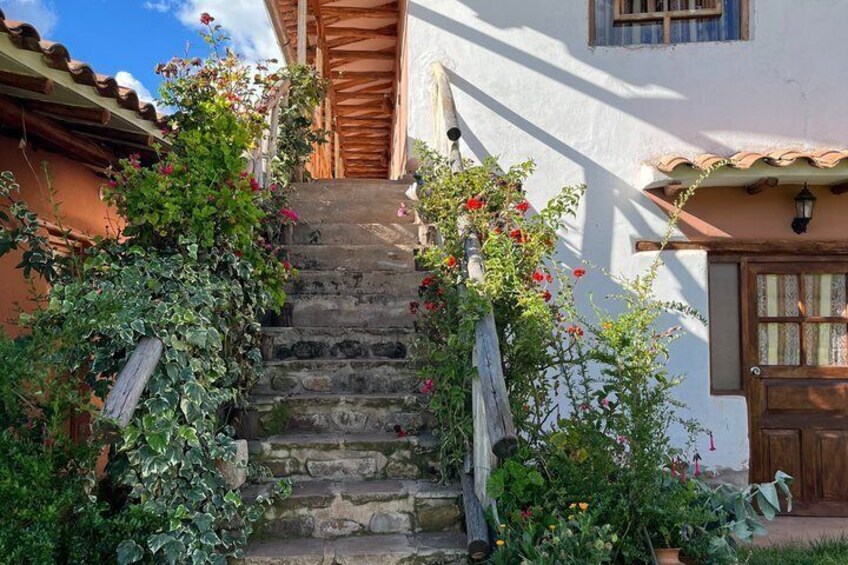 A stone staircase leading to a white building with a wooden door and window shutters. 2