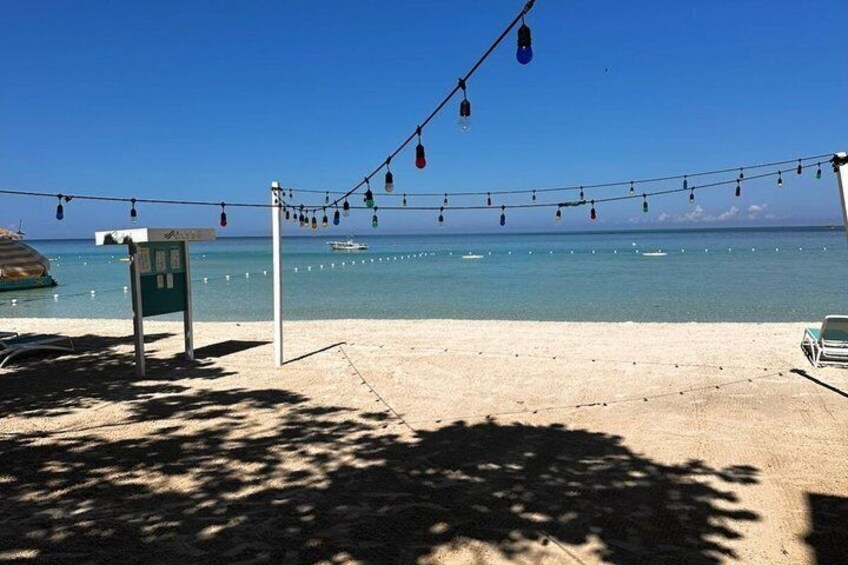 A beach with string lights, a lifeguard stand, and a clear blue sky. 3