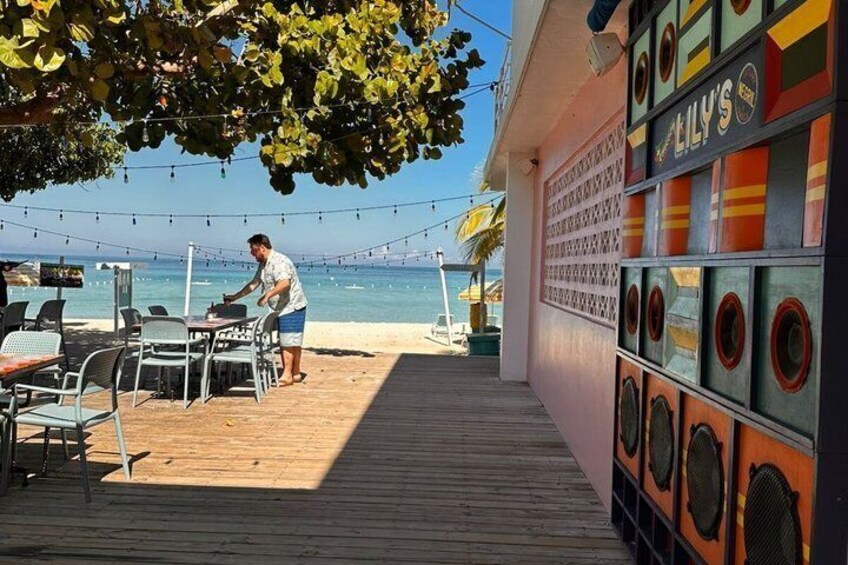 A beachside restaurant with outdoor seating, a wooden deck, and a view of the sea. 2