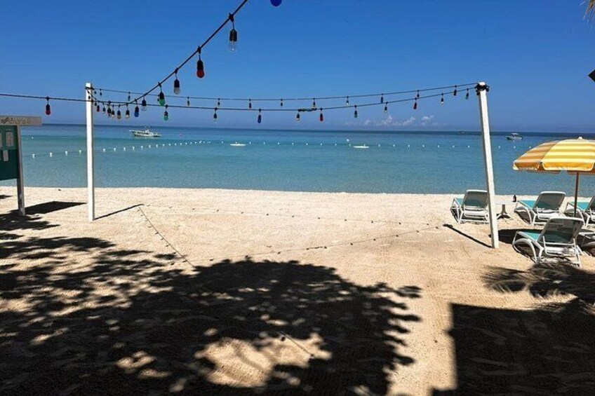 A beach with string lights, umbrellas, and lounge chairs. 4