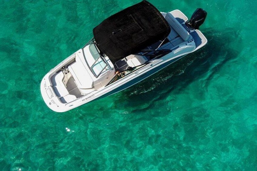 A white motorboat with a black canopy on a clear turquoise sea. 2