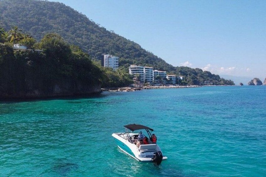 A boat on turquoise water with a mountainous coastline in the background. 2