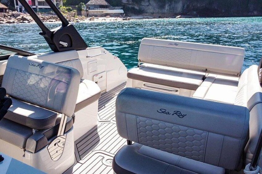 A boat interior with seating labeled 'Sea Ray' and a view of calm water and rocky shoreline. 3