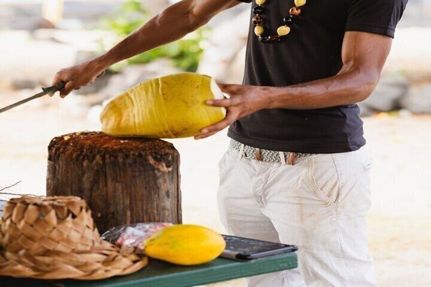 A person carving a yellow fruit on a wooden stump. 4