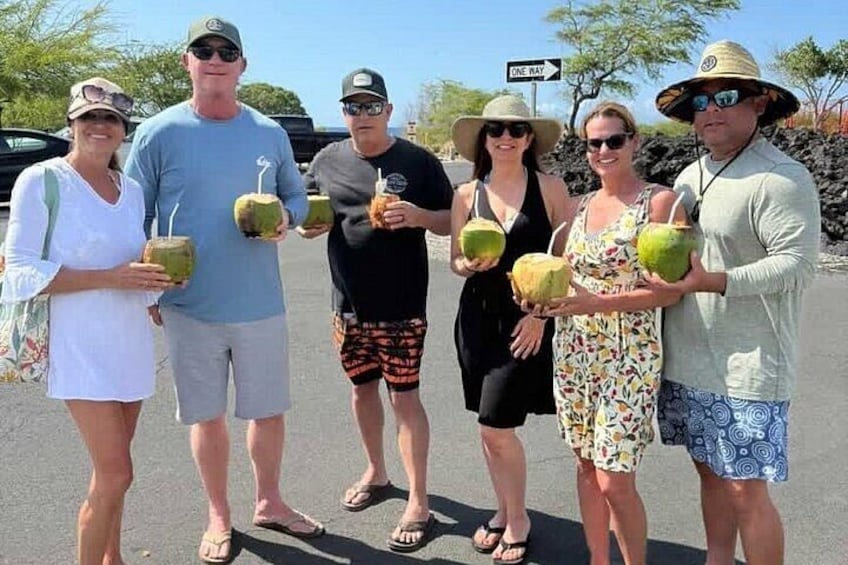 A group of people holding coconuts in a parking lot. 4