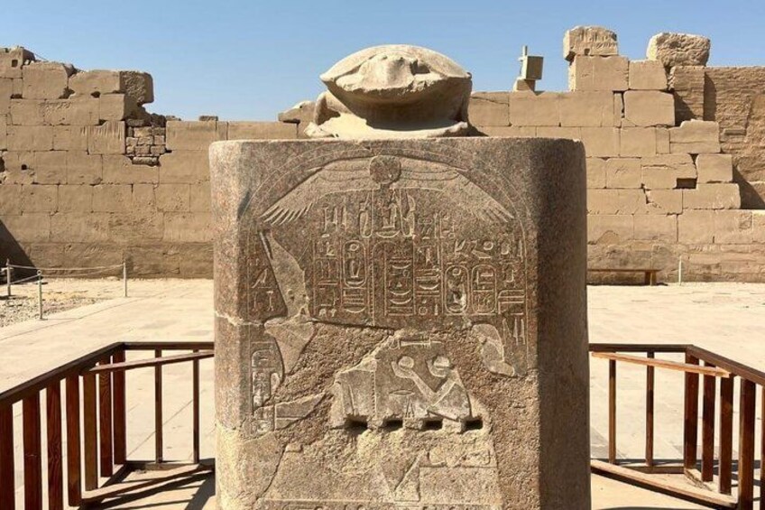 An ancient Egyptian stone monument with hieroglyphics and a seated figure. 3