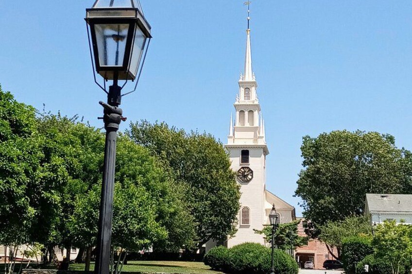 A church with a clock tower, surrounded by trees and a street lamp. 3