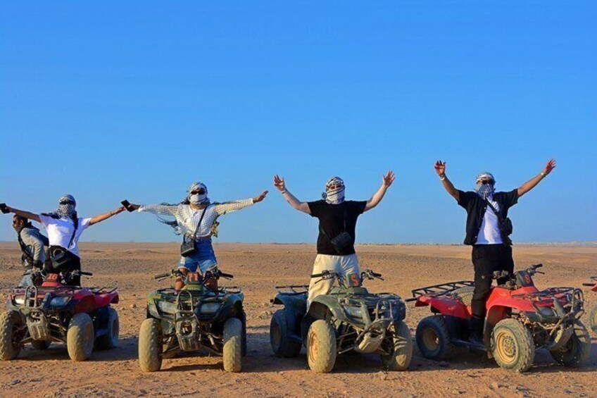 Four people on quad bikes in a desert landscape. 5