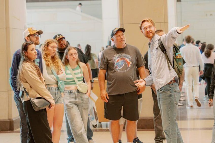 A group of people in a public indoor space with a tiled floor and a glass partition in the background. 1