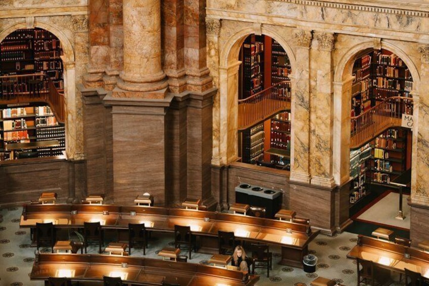 A grand library with marble columns, bookshelves, and reading tables. 5