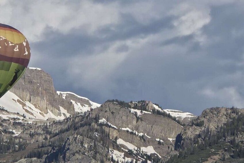 A hot air balloon, snow-capped mountains, and a cloudy sky. 4