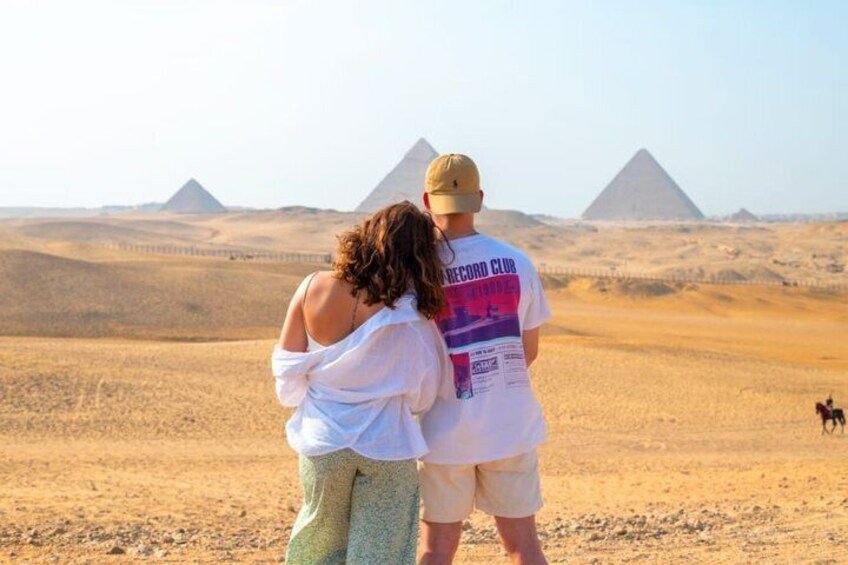 A couple standing with the pyramids in the background. 3