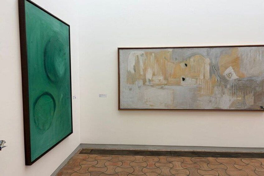 Two large abstract paintings on a white wall, a patterned floor, and a vent. 3