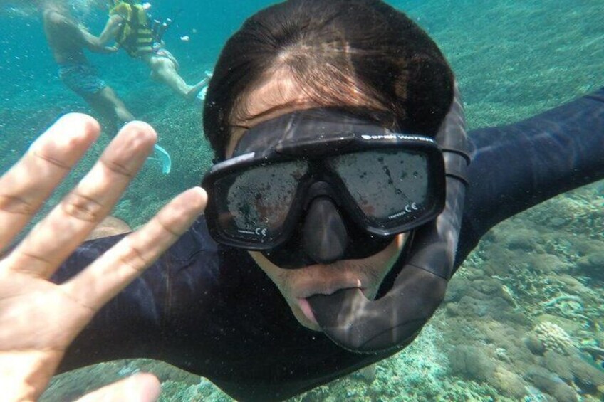 A person underwater, wearing a snorkel mask and fins, with a hand raised. 2