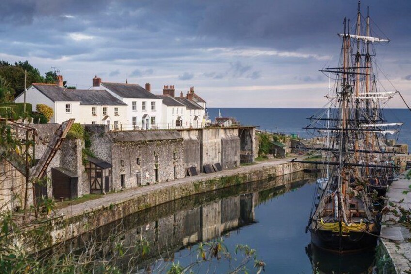 A historic building, a tall sailing ship, and a calm waterway. 1