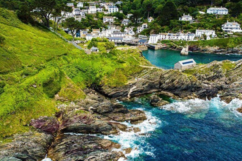 A coastal village with houses on a hillside, rocky shoreline, and a clear blue sea. 2