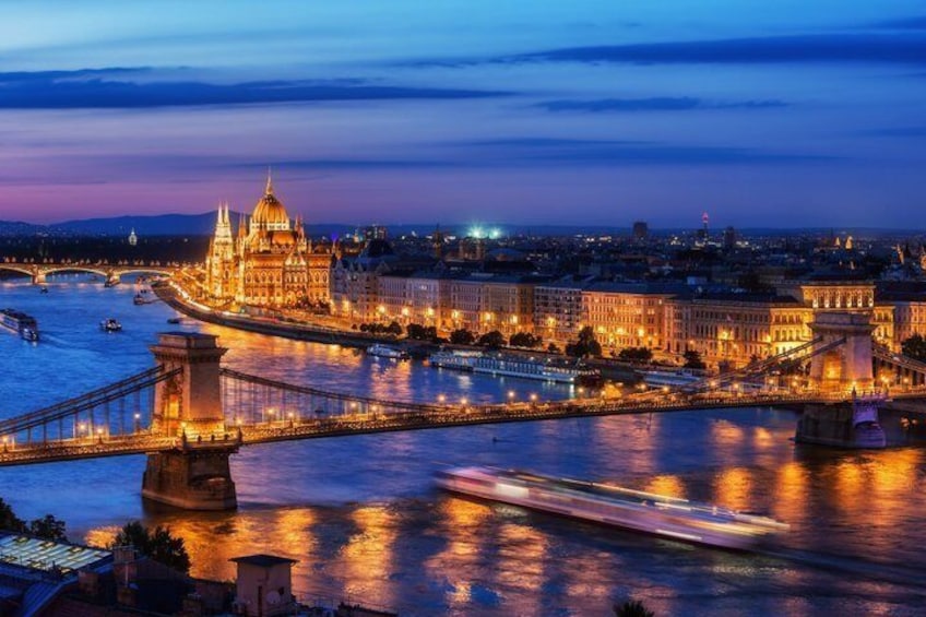 A nighttime cityscape with a prominent illuminated building, a bridge, and a river. 1