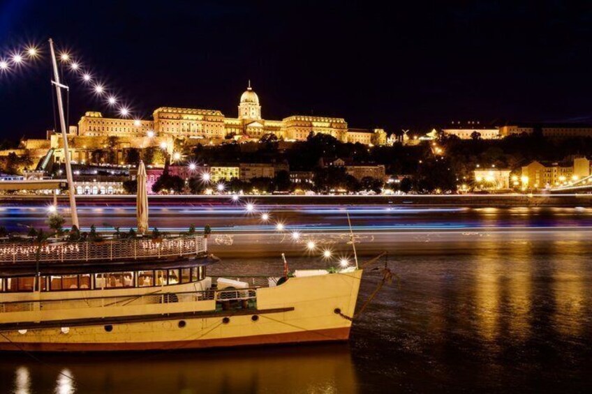 A boat docked near a historic building with a dome, illuminated by night lights. 3