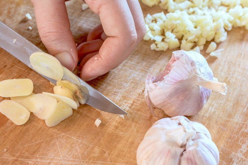 A person chopping garlic on a wooden cutting board. 3