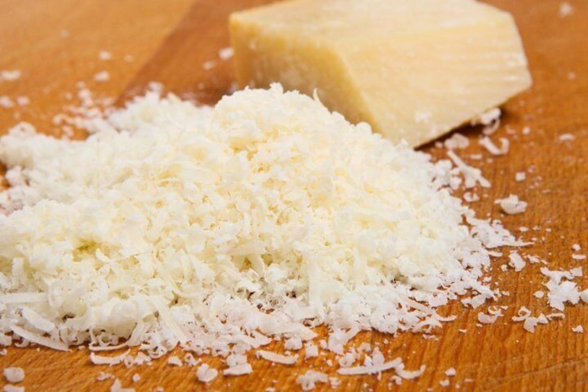 Shredded cheese and a block of cheese on a wooden surface. 2