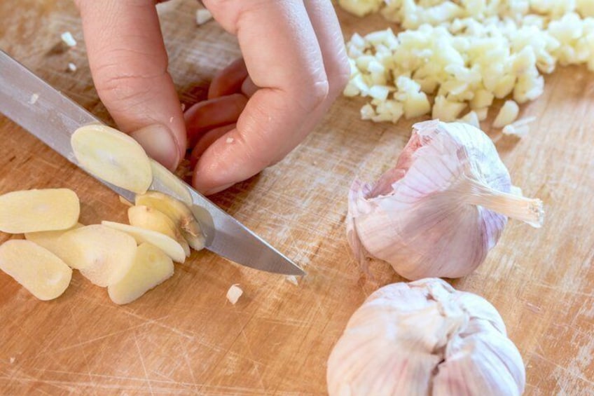A person chopping garlic on a wooden cutting board. 4