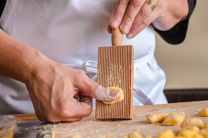 A person using a wooden rolling pin to flatten dough on a floured surface. 1