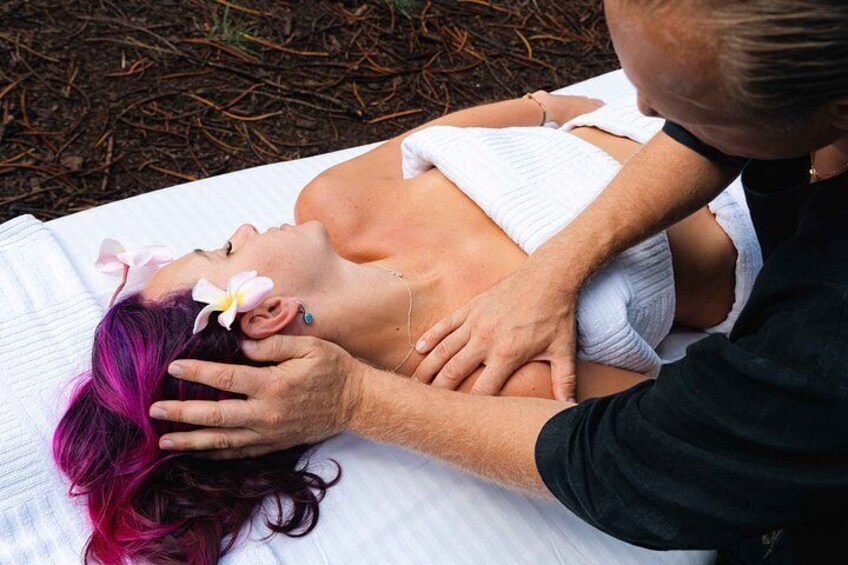 A person lying on a white surface outdoors, with another person attending to them. 4