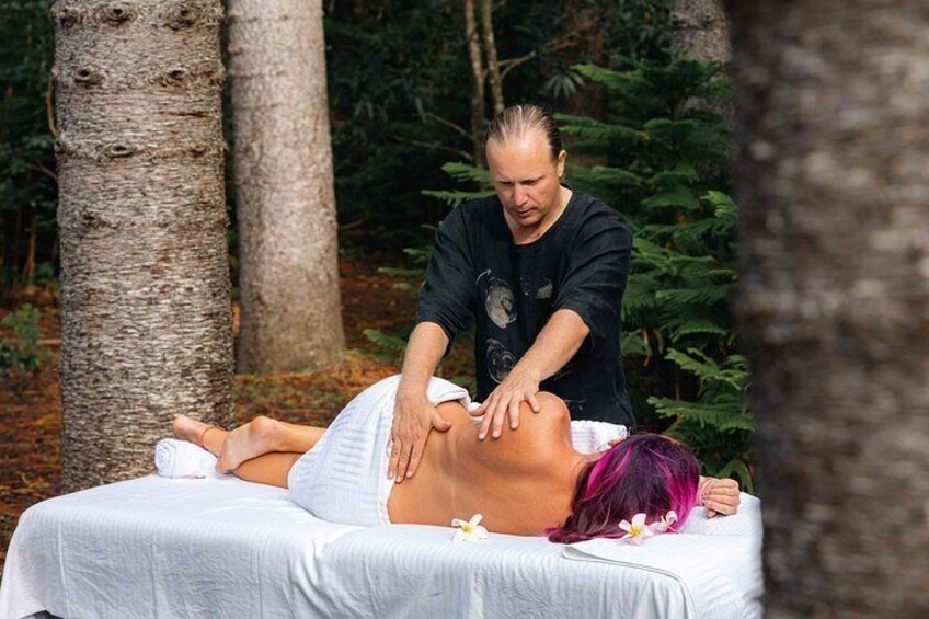 A person receiving a massage outdoors with trees in the background. 2