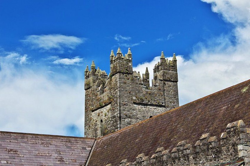 A historic stone tower with multiple turrets against a clear blue sky. 5