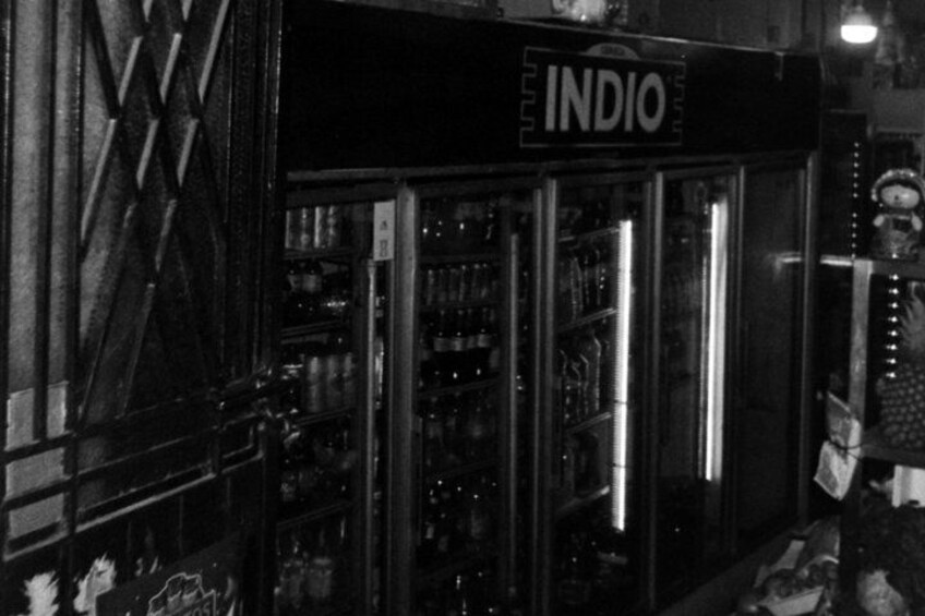 A vintage storefront with a sign reading 'INDIO' and a display of bottled beverages. 2