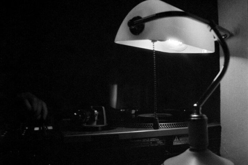 A desk with a lamp, a keyboard, and a computer monitor in a dimly lit room. 4
