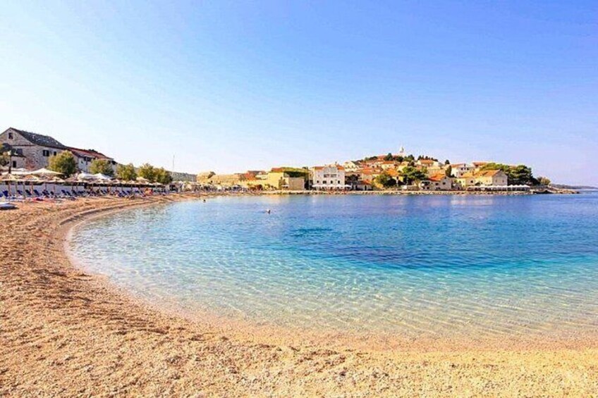 A coastal town with a sandy beach and clear blue waters. 1
