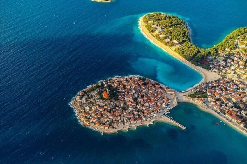 An aerial view of a coastal town with a central island, surrounded by clear blue waters and smaller islands. 3