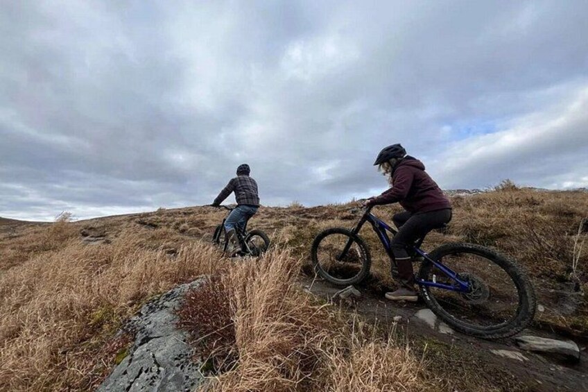 Two cyclists on a dirt trail with a cloudy sky. 3