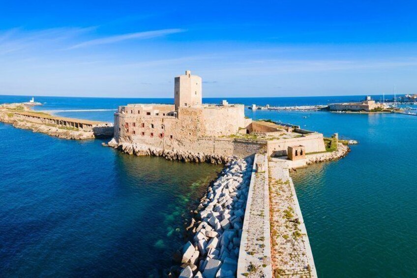 A coastal fortification with a central tower, surrounded by water and a clear sky. 2
