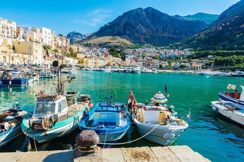 A harbor with boats docked, a town in the background, and mountains in the distance. 3