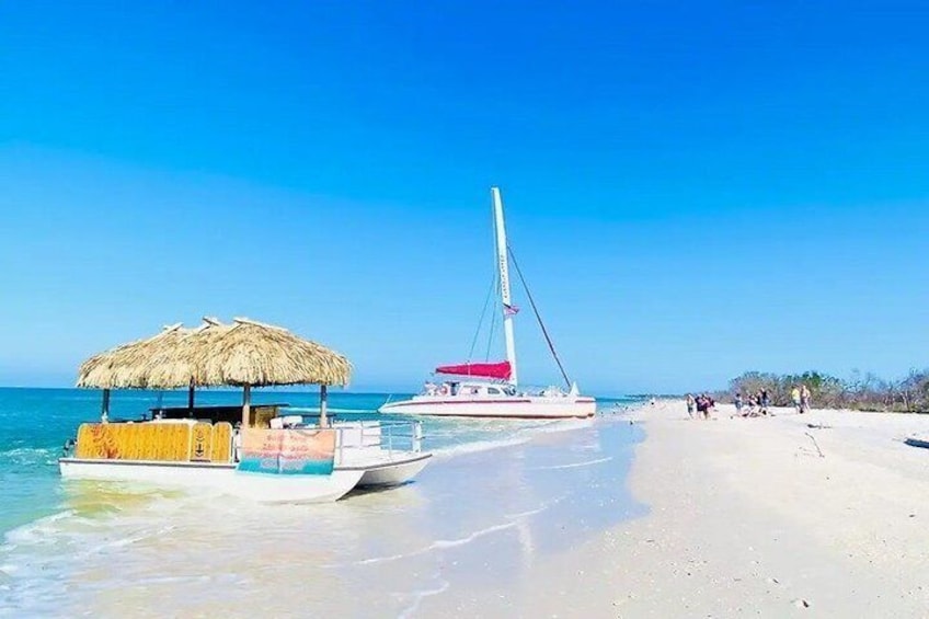A beach with a thatched-roof structure, a sailboat, and a sandy shore. 1