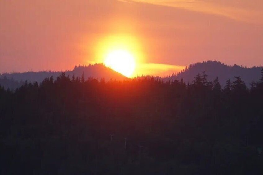 A sunset over a forested mountain range. 1