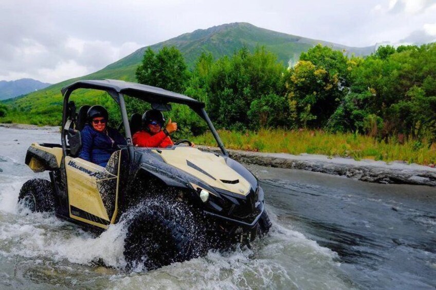 A vehicle navigating a river surrounded by lush greenery and hills. 5