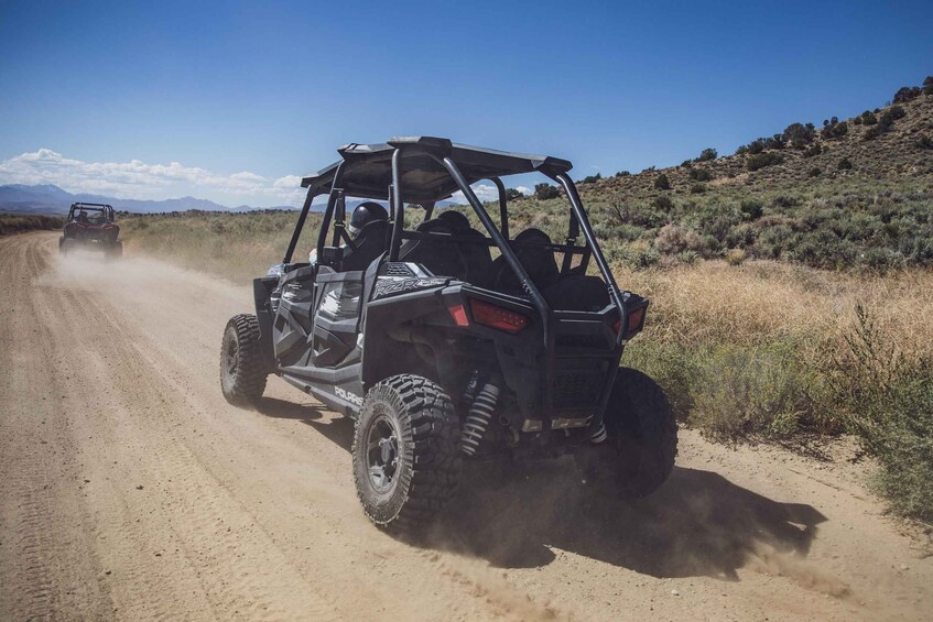 Two off-road vehicles on a dirt road with a hilly landscape in the background. 5