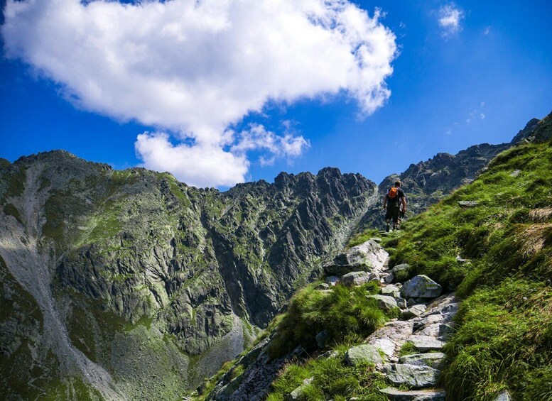 A hiker on a rocky mountain trail with steep cliffs and sparse vegetation. 5