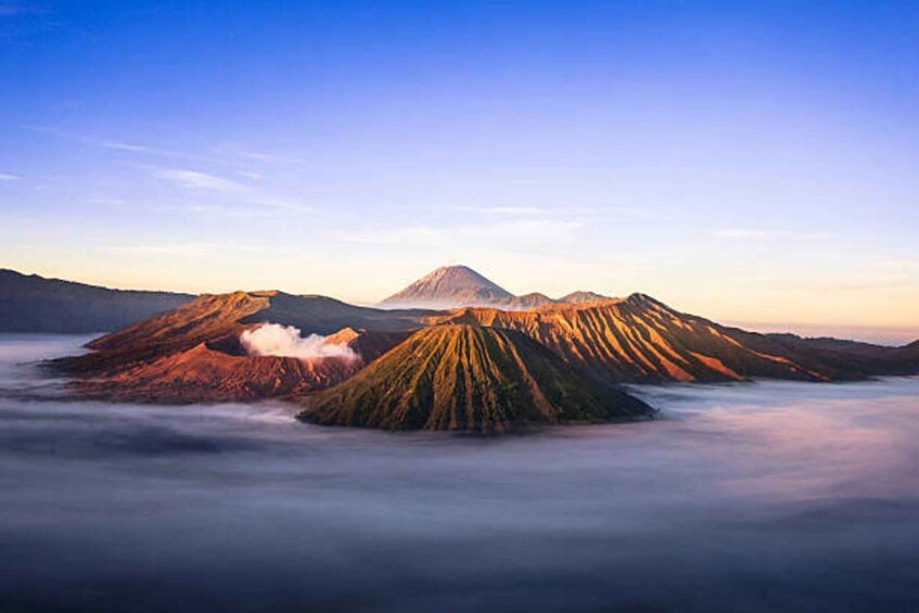 A volcanic landscape with a prominent mountain peak and a cloud-covered foreground. 2