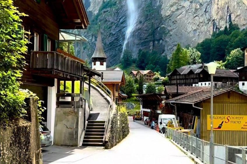 A mountain village with wooden houses, a church, and a waterfall. 1